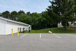 Holland apartment for rent - A parking lot with a white building and yellow bollards.