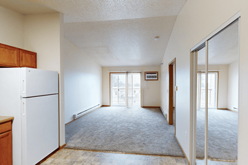 Williston apartment for rent - A white refrigerator sits in a kitchen next to a wooden cabinet.