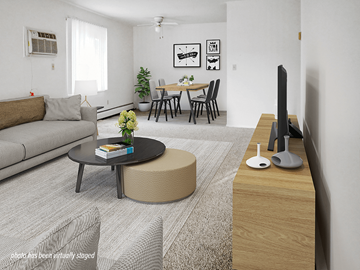 Brooklyn Park apartment for rent - A living room with a grey sofa, a black coffee table, a round ottoman, a wooden TV stand, and a dining table with chairs.