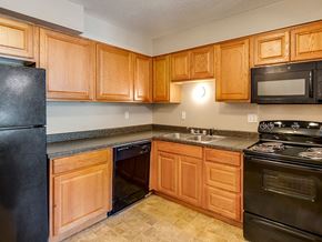 Kansas City apartment for rent - a kitchen with black appliances and wooden cabinets