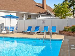 Topeka apartment for rent - a swimming pool with blue chairs and umbrellas in front of a hotel pool