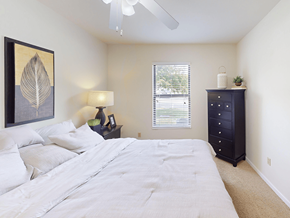 Valley Park apartment for rent - A bedroom with a large bed, a nightstand with a lamp, and a painting on the wall.