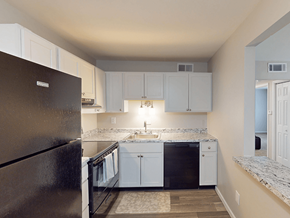 Fenton apartment for rent - A kitchen with a black refrigerator and white cabinets.