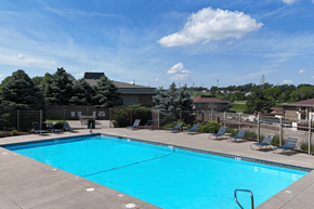 Omaha townhouse for rent - A large blue swimming pool surrounded by a fence and lounge chairs.