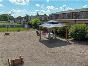 Waite Park apartment for rent - A sandy playground area with a wooden structure and a black umbrella.