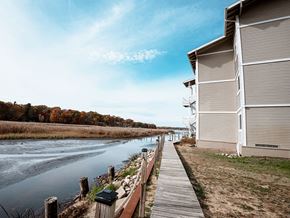 Norton Shores apartment for rent - A wooden walkway runs alongside a body of water with a building on the right.