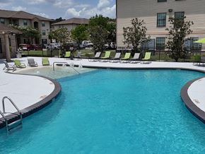 Denham Springs apartment for rent - A swimming pool with a black fence and green chairs.