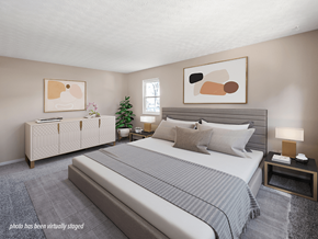 Newark townhouse for rent - A bedroom with a large bed and a nightstand with a lamp.