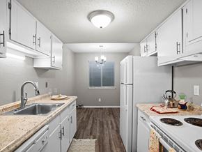 Topeka townhouse for rent - a kitchen with white cabinets and a sink and a refrigerator