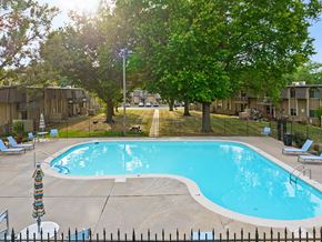 Topeka townhouse for rent - a swimming pool with chairs around it and trees