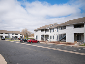 Mcpherson apartment for rent - A parking lot with a red car parked in front of a white building.