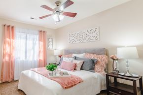 Omaha apartment for rent - A bedroom with a bed, a fan, and a nightstand with a lamp.