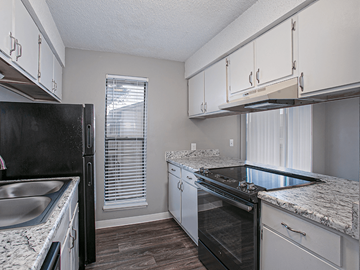 Wichita apartment for rent - a kitchen with white cabinets and black appliances