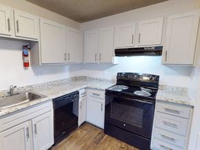 Greeley apartment for rent - A kitchen with white cabinets and a black stove top oven.