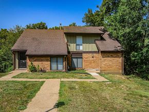 Florissant townhouse for rent - A house with a brown roof and a brick exterior is surrounded by greenery.