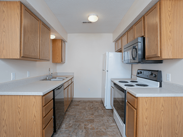 Wichita townhouse for rent - an empty kitchen with wood cabinets and a white refrigerator