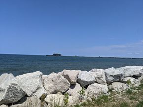Sandusky apartment for rent - A rocky shoreline with a body of water and a distant island.