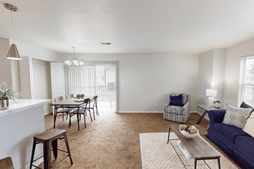 Florissant apartment for rent - A living room with a blue couch and a dining table.