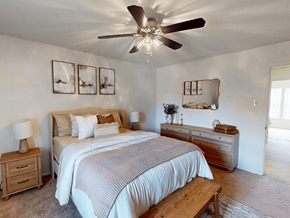 Ballwin townhouse for rent - A bedroom with a bed, nightstand, and a ceiling fan.