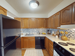 Ballwin townhouse for rent - A kitchen with wooden cabinets and a black refrigerator.