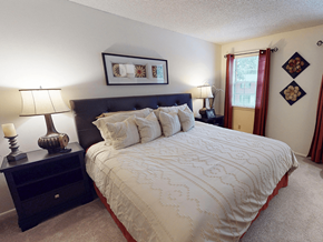 Sappington townhouse for rent - A bedroom with a large bed and a nightstand with a lamp.