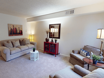 Sappington townhouse for rent - A living room with a grey couch, a red side table, and a painting on the wall.