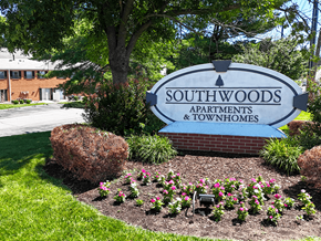 Sappington townhouse for rent - A sign for Southwoods Apartments and Townhomes is surrounded by flowers and greenery.