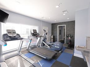 Fayetteville apartment for rent - A modern gym with treadmills, elliptical machines, and a stationary bike.