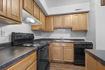 Cedar Rapids apartment for rent - A kitchen with wooden cabinets and black appliances.
