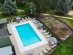 Greeley apartment for rent - A pool surrounded by a fence and a garden.