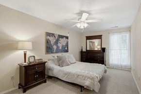St. Louis apartment for rent - A bedroom with a bed, dresser, and ceiling fan.