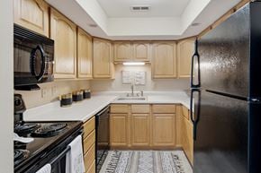 St. Louis apartment for rent - A kitchen with wooden cabinets and a black refrigerator.