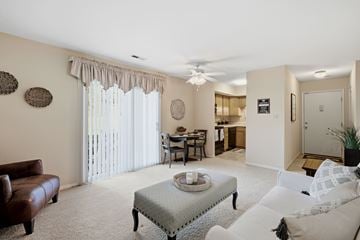 St. Louis apartment for rent - A living room with a brown leather couch, a white sofa, a coffee table, and a dining table with chairs.
