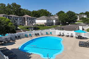 Omaha townhouse for rent - A large swimming pool surrounded by a white fence and lounge chairs.