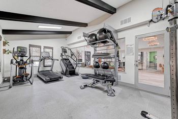 A gym with a variety of equipment including treadmills, weights, and exercise machines.