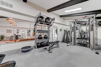 A gym with a variety of equipment including weights and a rowing machine.