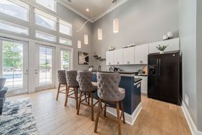 Greensboro apartment for rent - Clubhouse kitchen with a black refrigerator and a dining table with chairs.