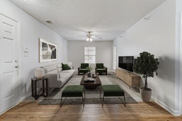 Fayetteville apartment for rent - A living room with a grey couch, a green chair, a brown coffee table, and a potted plant.