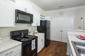 Kernersville apartment for rent - a kitchen with white cabinets and a black stove top oven