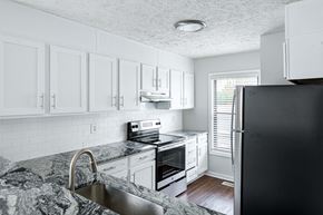 Spring Lake apartment for rent - a kitchen with white cabinets and black appliances and a granite counter top