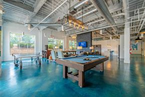 Chapel Hill apartment for rent - A pool table in a room with a high ceiling and exposed pipes.
