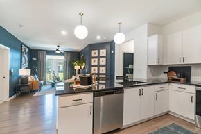 Mooresville apartment for rent - A modern kitchen with white cabinets and a black countertop at Evolve Lake Norman apartments in Mooresville, NC