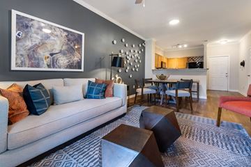Greensboro apartment for rent - A living room with a grey couch and a large abstract painting on the wall.