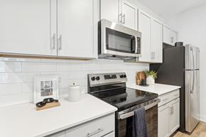 Shallotte apartment for rent - A modern kitchen with white cabinets and black appliances.