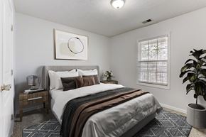 Fayetteville apartment for rent - A bedroom with a bed, nightstand, and a plant.