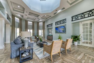 Palm Coast apartment for rent - A living room with a grey sofa, wooden chairs, and a large painting on the wall.