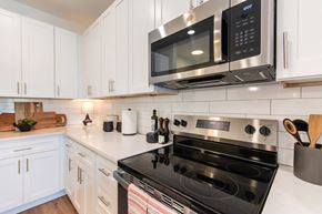 Greensboro apartment for rent - A modern kitchen with a black stove top oven and white cabinets.