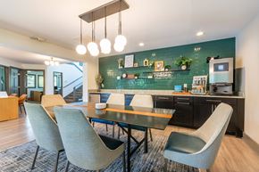 Greensboro apartment for rent - A modern clubhouse kitchen with a dining table and chairs at Hawthorne at Oak Ridge in Greensboro, NC.