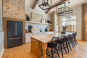 Whitsett apartment for rent - the kitchen has a large island with chairs and a black refrigerator