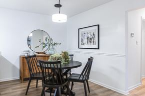 Savannah apartment for rent - A dining room with a round mirror, a table with chairs, and a framed picture on the wall.
